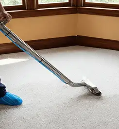 Steam carpet cleaning technician using a hot-water extraction wand on a residential carpet, wearing blue protective shoe covers Cincinnati, OH.